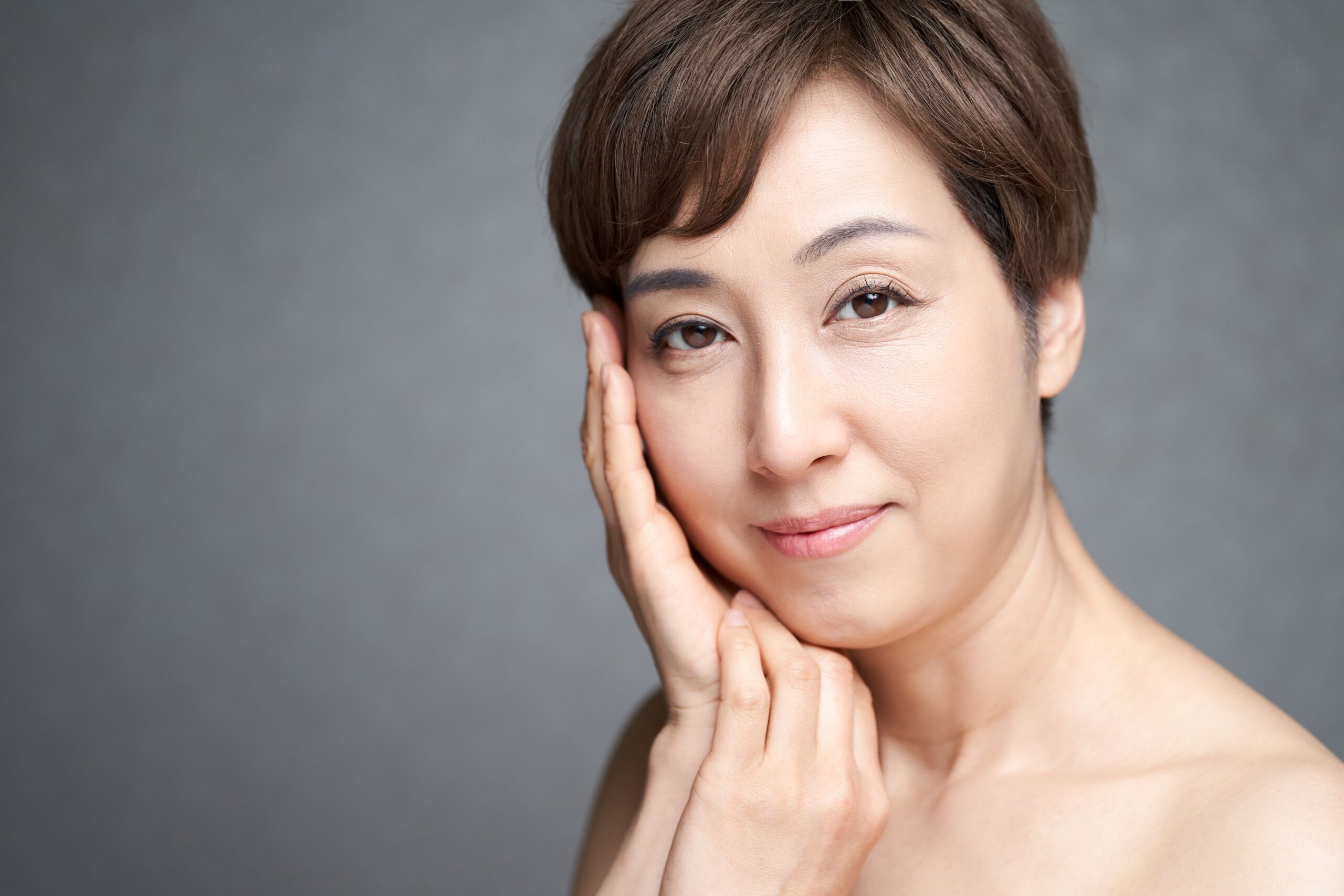 Woman with clear skin with both hands near face